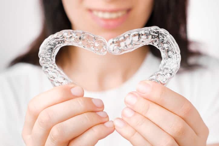 Focus is on a person holding two Invisalign plastic retainers.