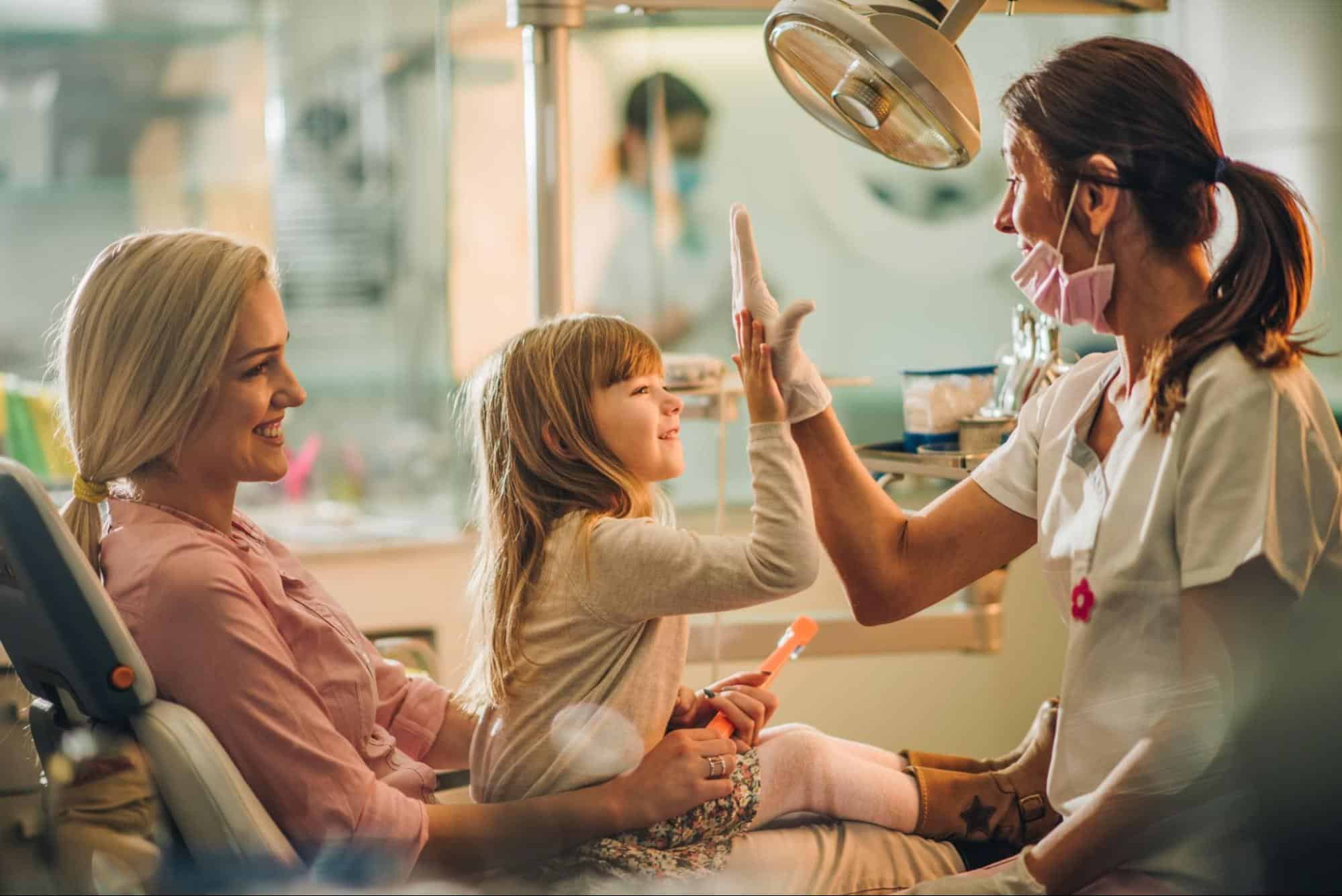 Dentist High-Fiving Child with Mother