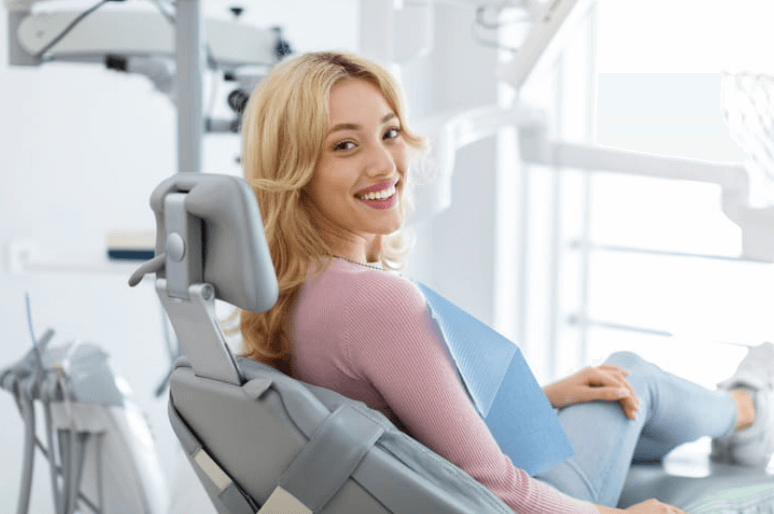 A woman sitting in the dentists office chair smiling