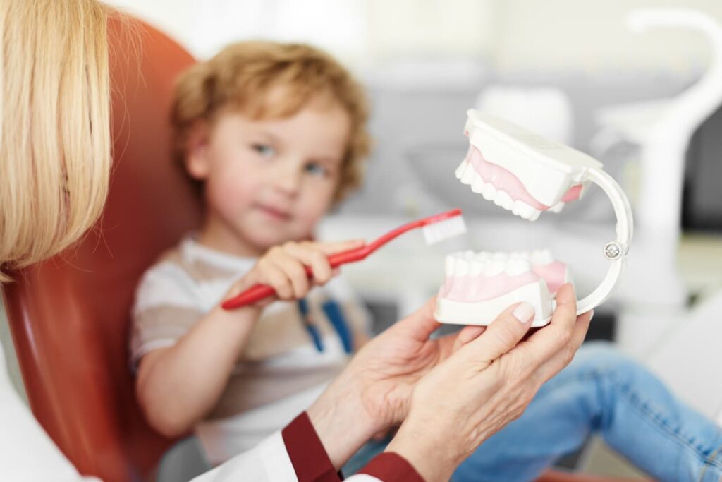 Pediatric Dentist teaching child how to brush teeth