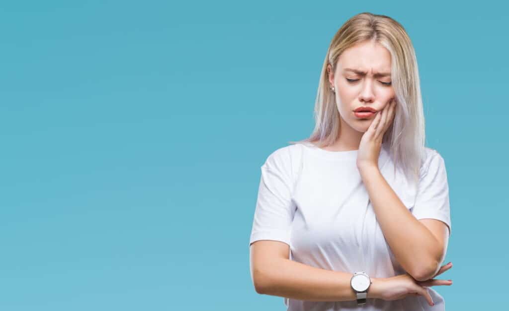 A woman holding her jaw in pain due to bad oral health.