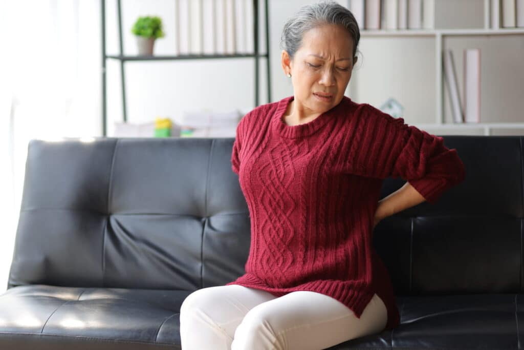 A woman with kidney disease holds her back while in kidney pain.