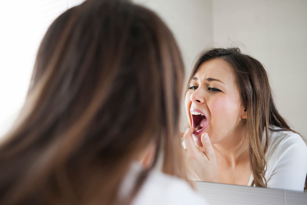 Woman checking teeth in mirror