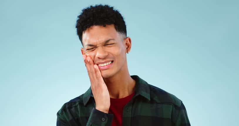 A man holding his face in pain due to a dental emergency. 