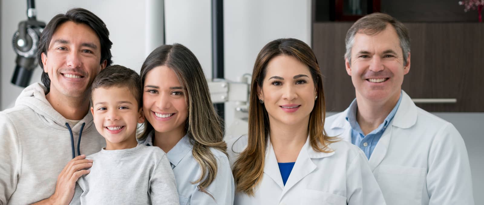 Absolute Dental dentist next to a family with health smiles