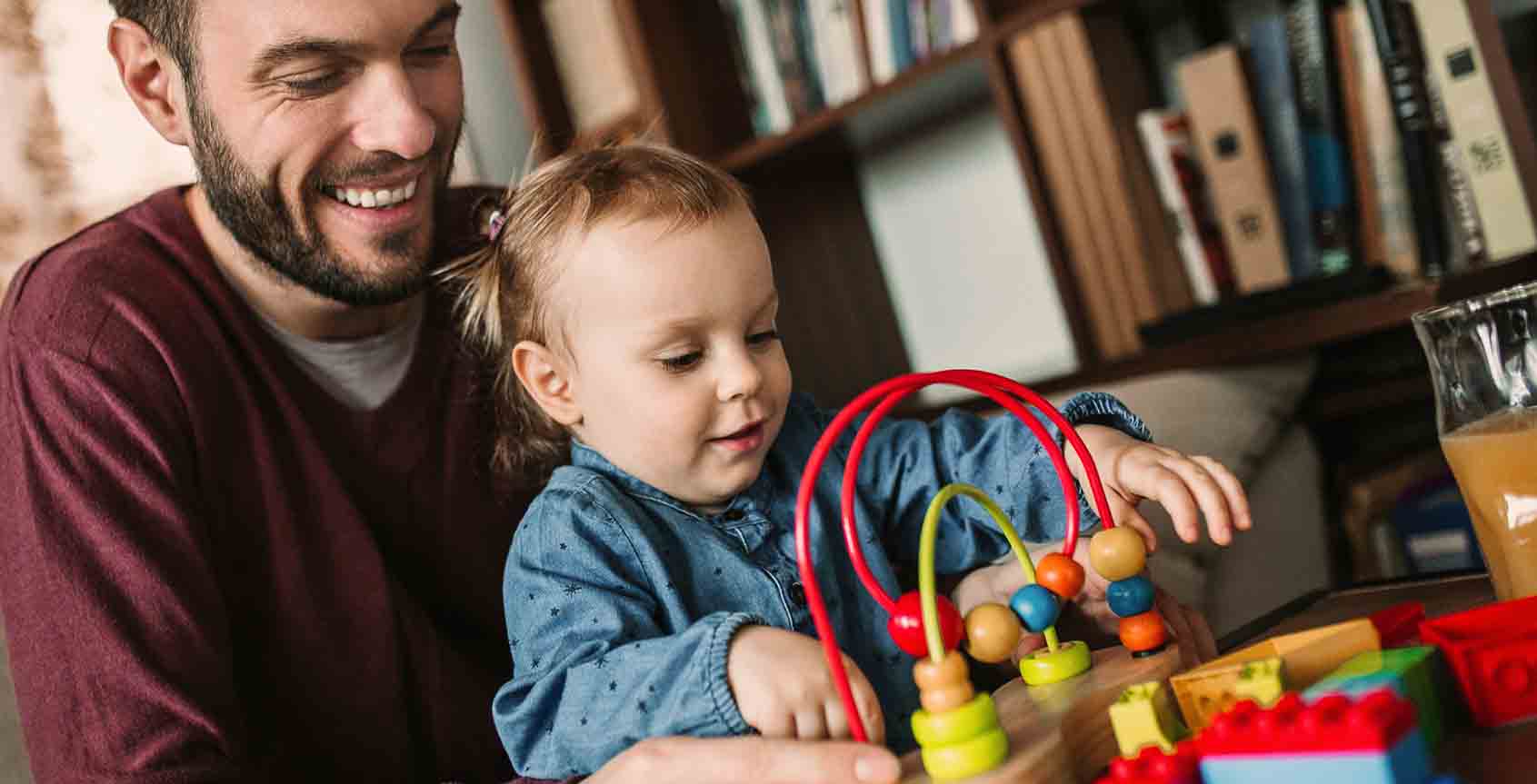 Man smiling at his daughter playing with toys