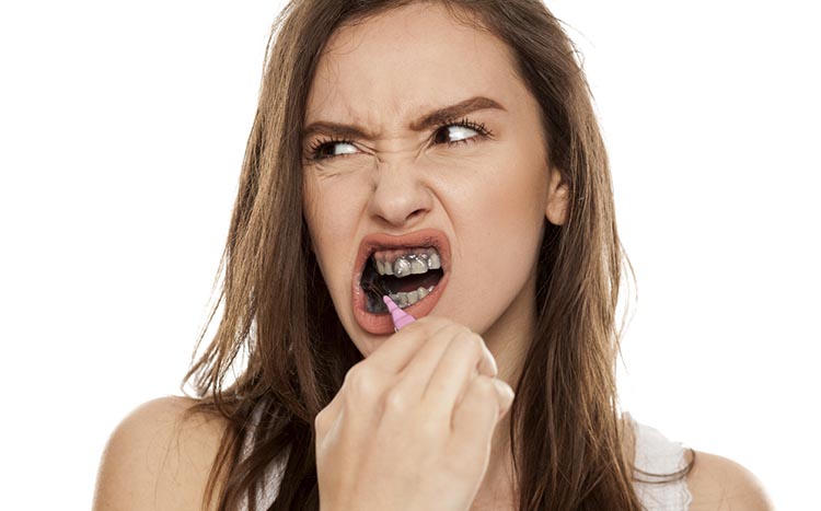 Woman using charcoal to whiten teeth 