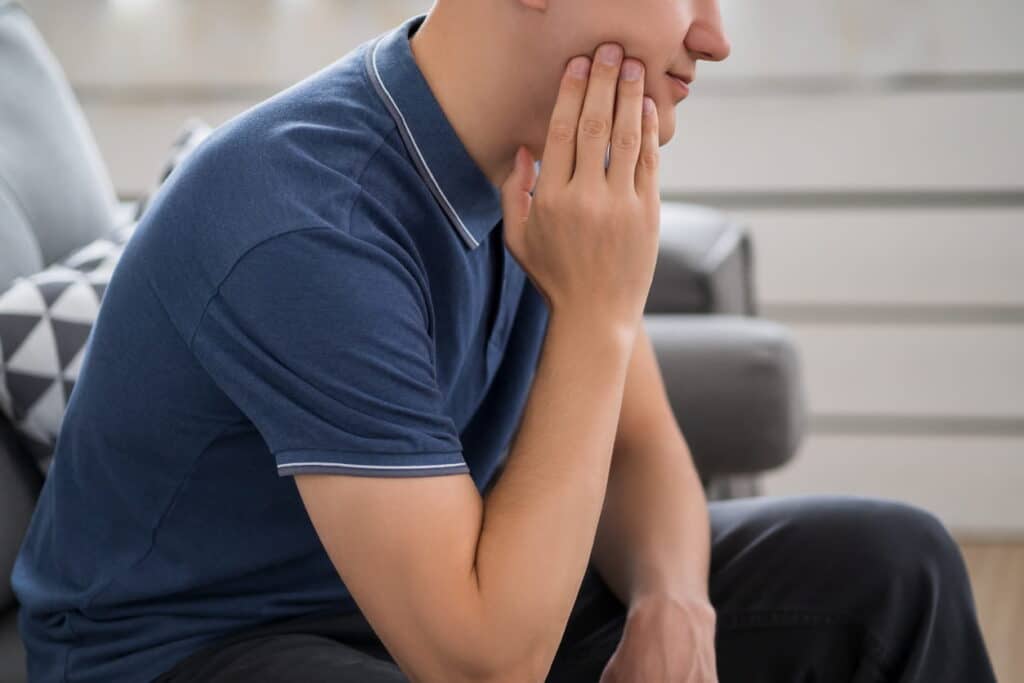 A man holding his jaw from wisdom tooth pain.