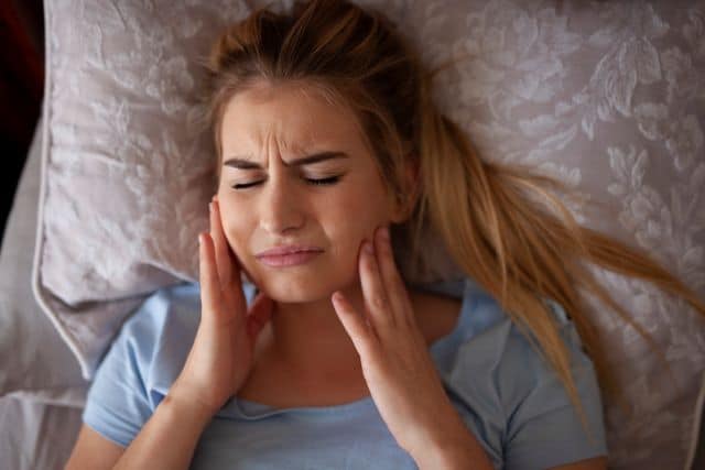 Woman in pain after grinding her teeth