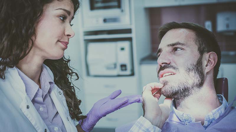 Man with tooth pain talking to dentist