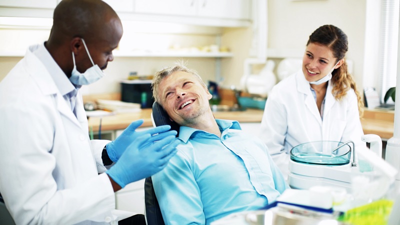Dentist talking to patient as assistant watches