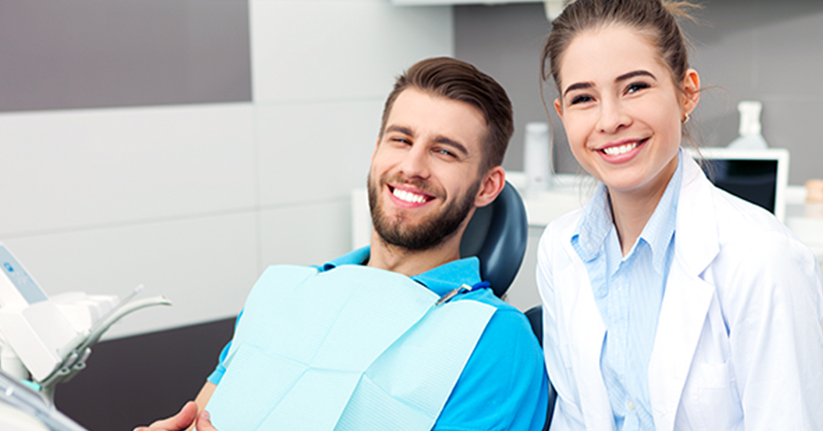 Happy patient in dental chair smiling with dentist