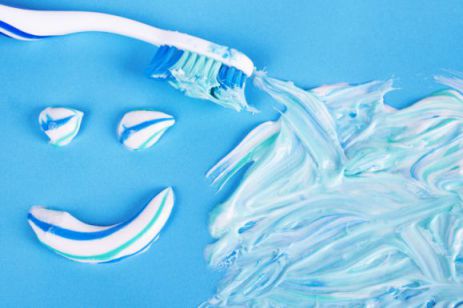 Toothbrush and smile made of toothpaste on blue background