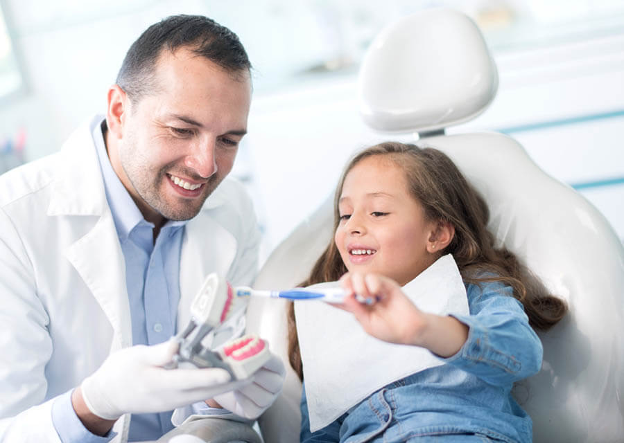 Dentist showing child how to brush teeth in Carson City
