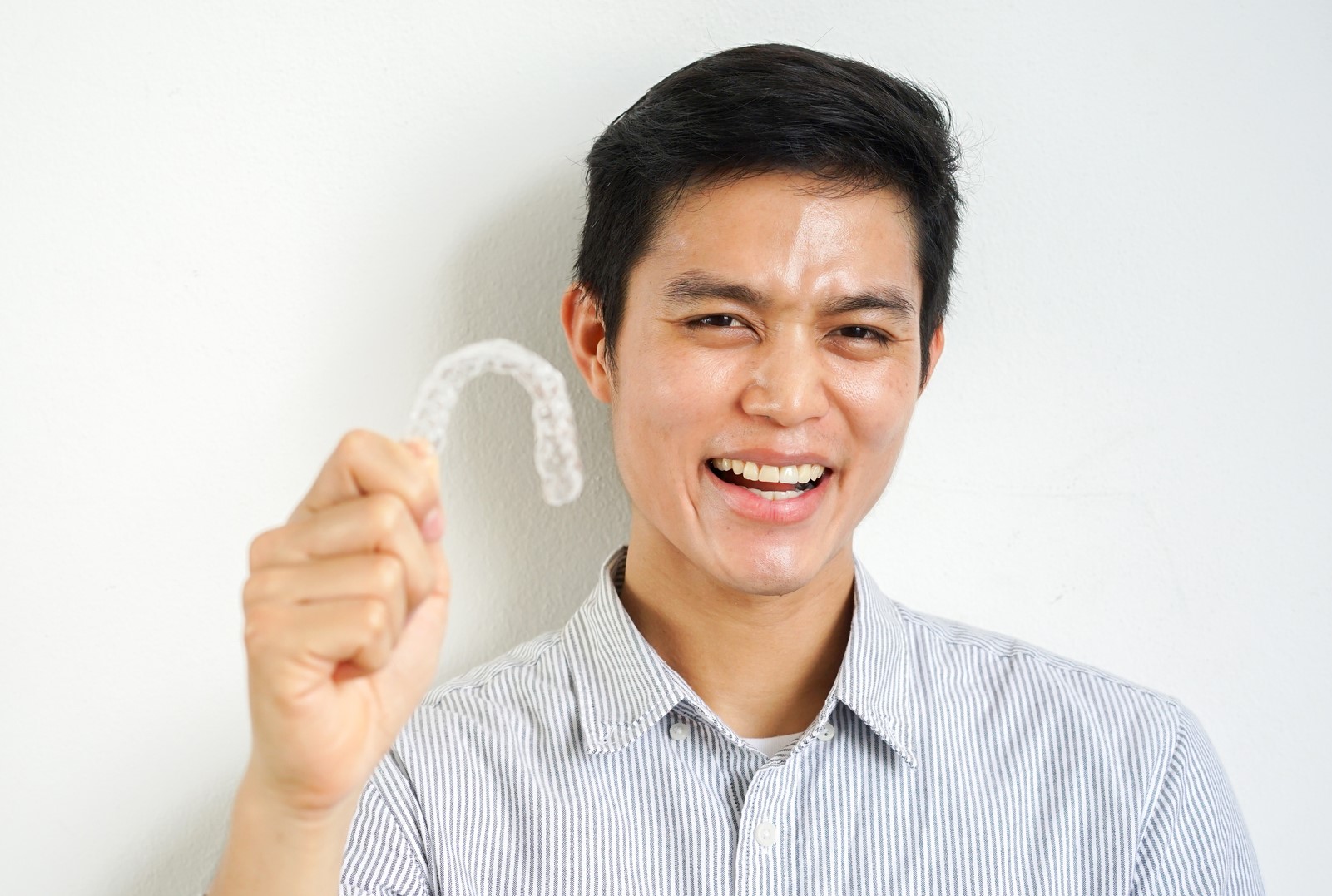 Man smiling holding clear aligners in Reno