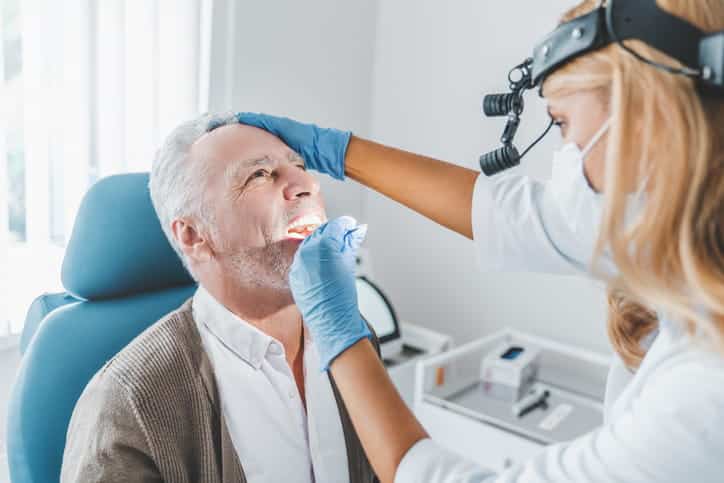 a dentist is examining a man's mouth.