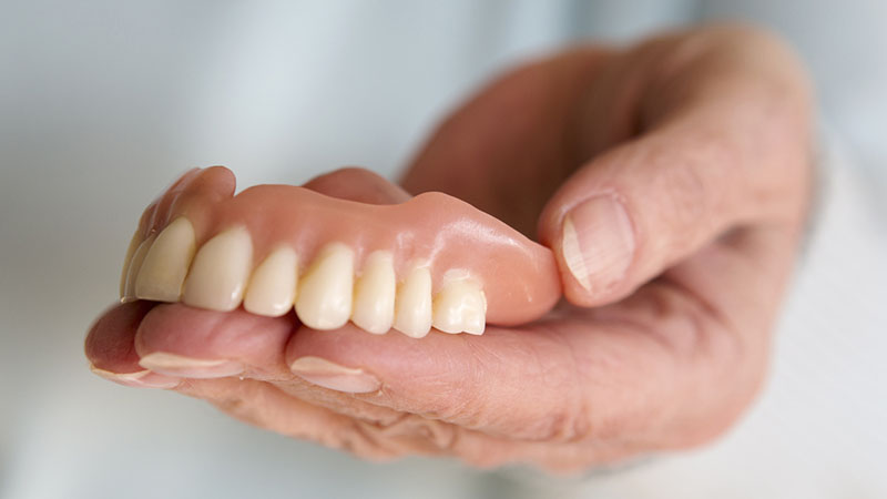Close up of woman holding dentures