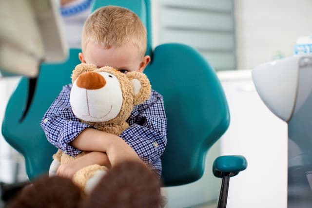 kid hugging a stuffed animal at the dentist