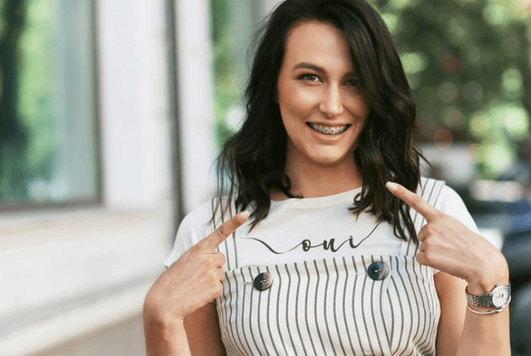 A woman smiling, showing off her braces