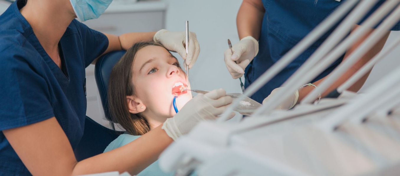 Pediatric dentistry. Female dentist examining a young girl.