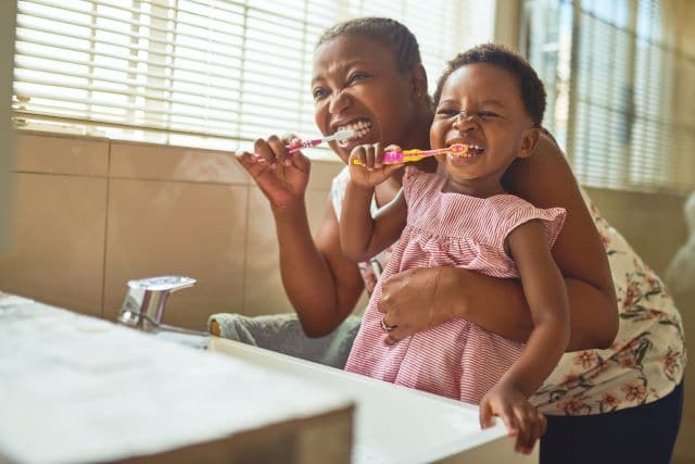 mother and daughter brushing their teeth together
