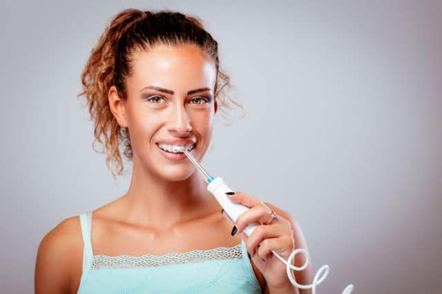 Young woman with braces using a water flosser