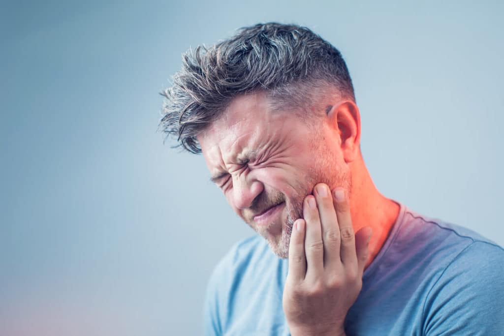Man with emergency toothache holding his cheek