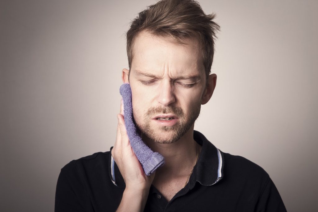 Man holding ice to swollen cheek after wisdom tooth extraction