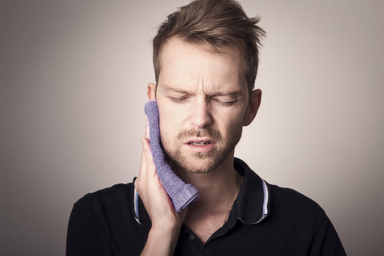 Man holding ice to swollen cheek after wisdom tooth extraction