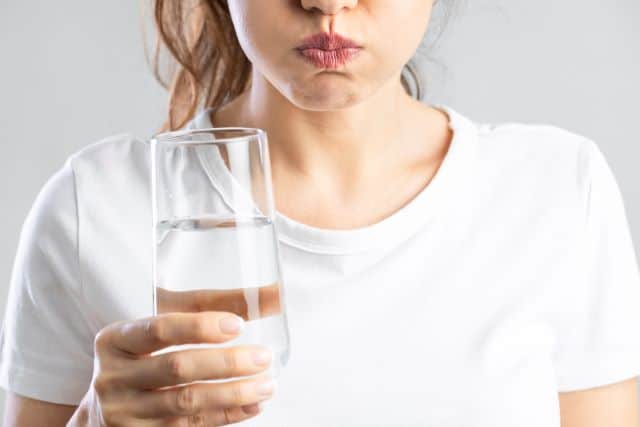 woman rinsing her mouth out with water with salt 