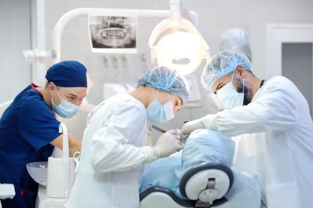 Dentists performing oral surgery on patient