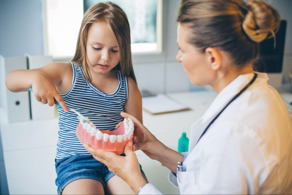 Dentist showing child how to brush teeth