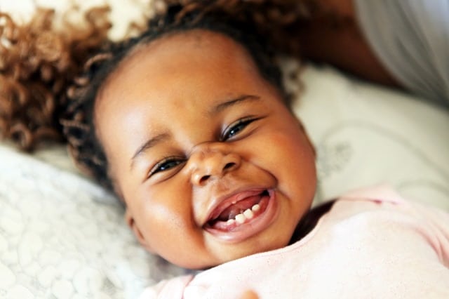 Baby smiling with four lower teeth in her mouth
