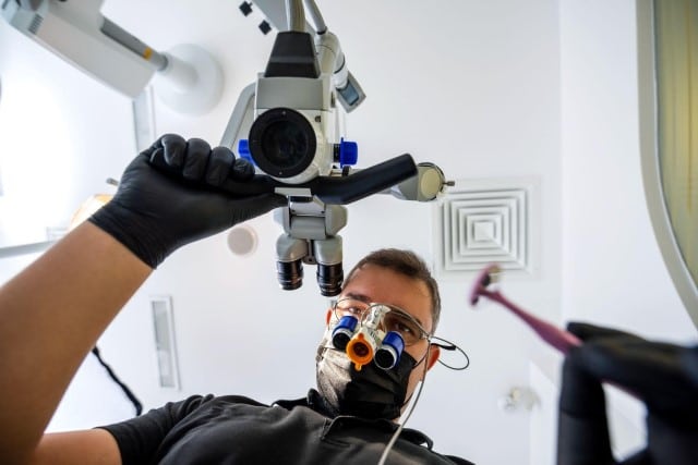 dentist with magnifying glasses looking over patient