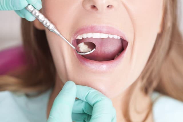 Patient getting teeth checked with dental tool