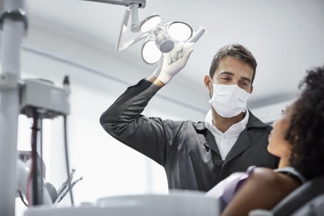 Dentist adjusting light over patient