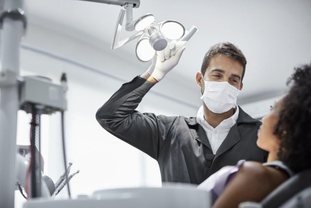 dentist adjusting light over patient