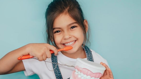young child brushing teeth with a blue background