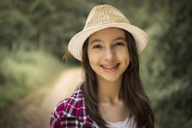 Teenage girl with braces and straw hat on outside
