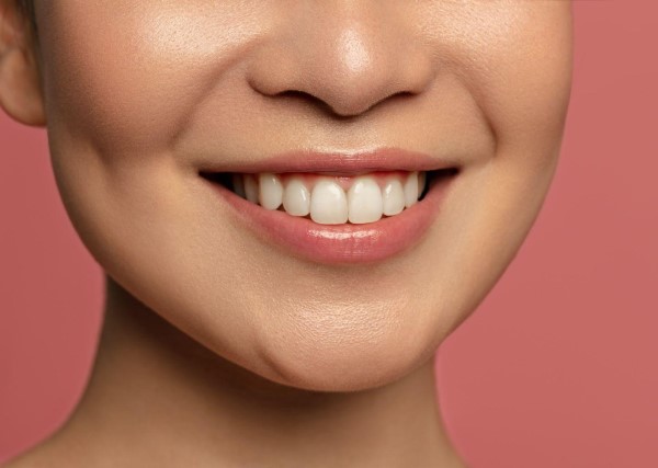 young lady smiling with veneers with pink background