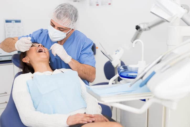 A dentist performing general dentistry services on his patient.