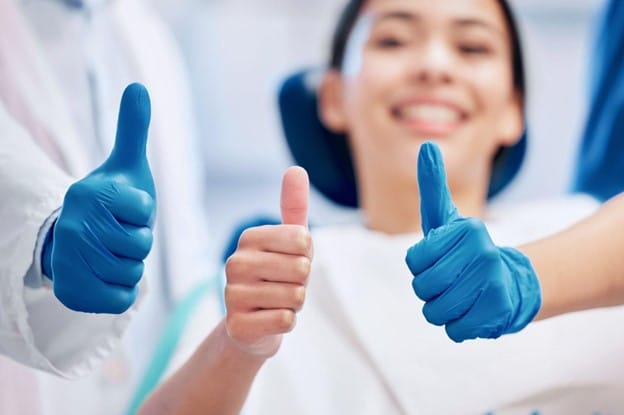 Woman and dentist giving thumbs up