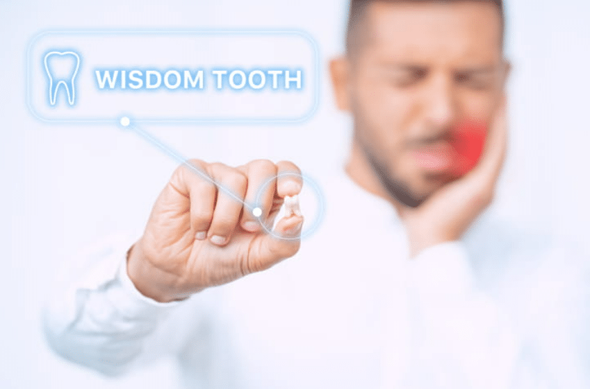 Man holding an extracted wisdom tooth that's labeled as such, along with him holding his jaw in pain.