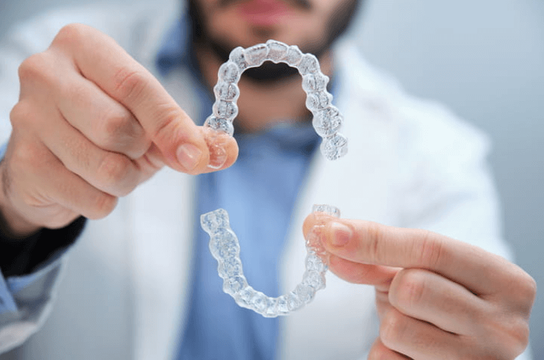 a dentist holding a pair of clear aligners