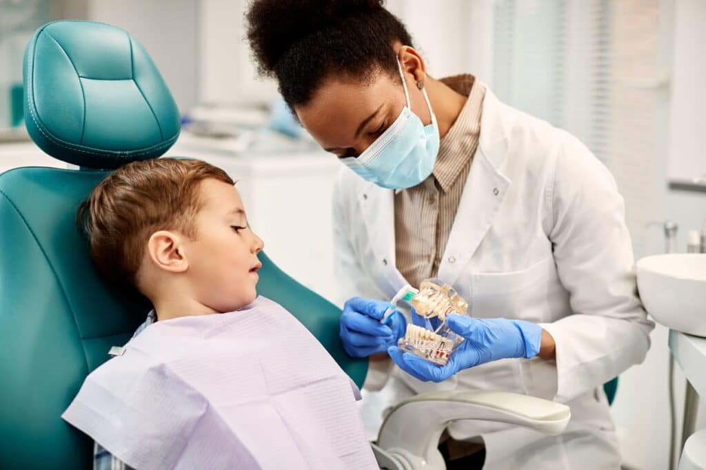 A general dentist showing a young patient a 3D model of a set of teeth.