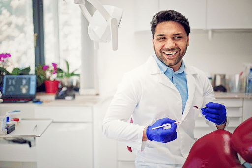 A dentist smiling after doing a dental implant on a patient.