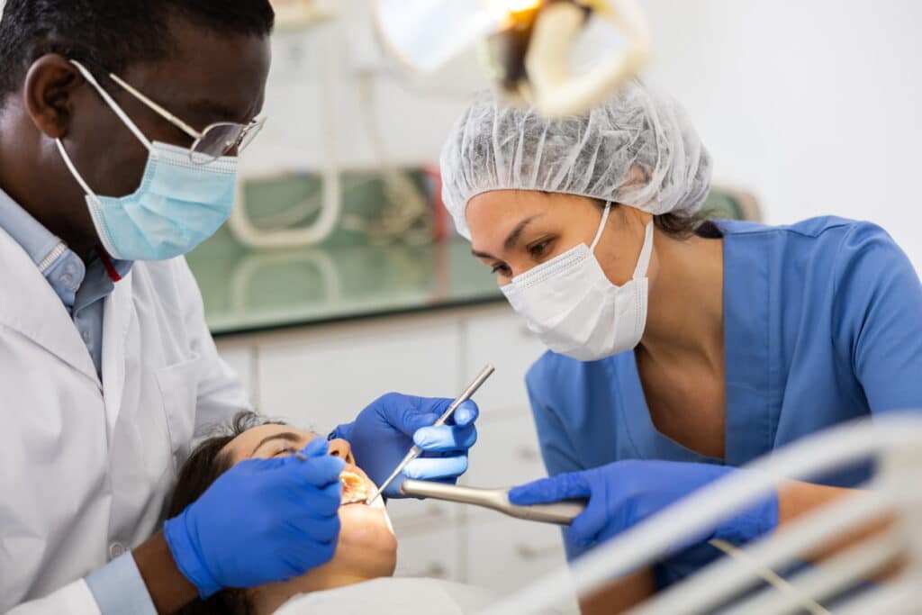 Two dental hygienists working with a patient.