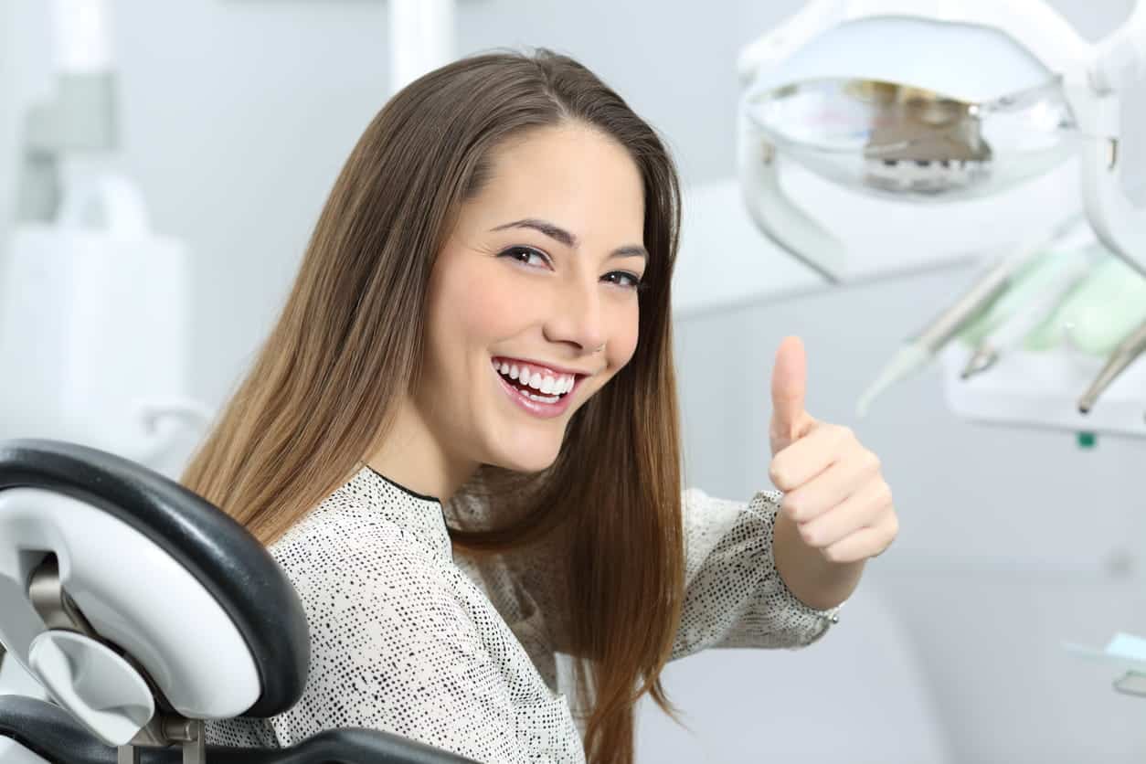 A woman smiling while sitting in a North Las Vegas dental chair and giving a thumbs up.