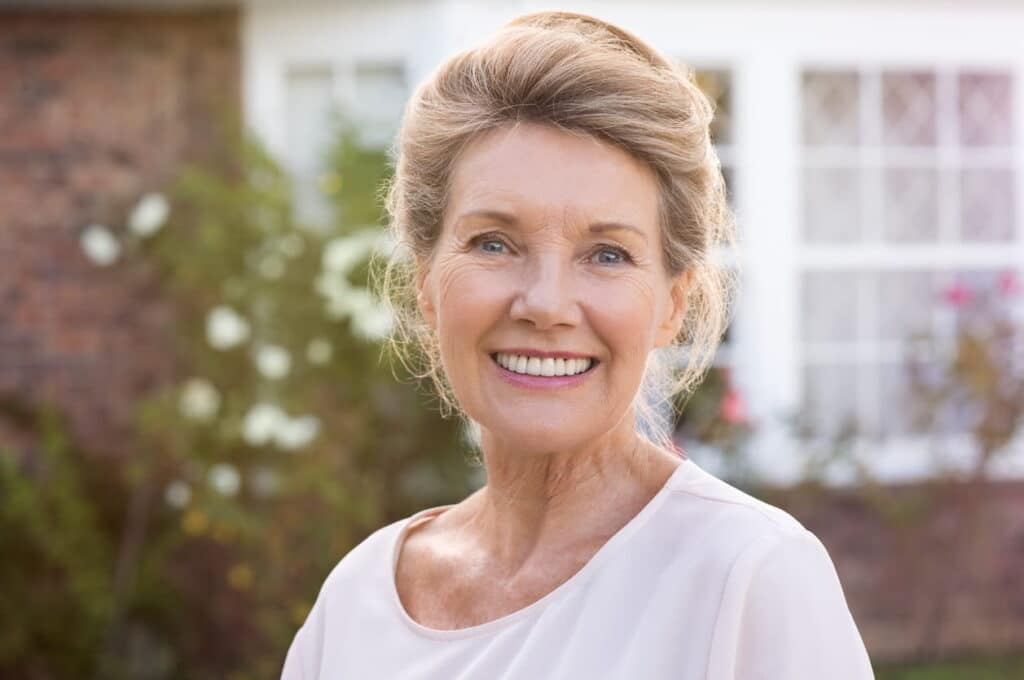 An elderly woman smiling with dentures.