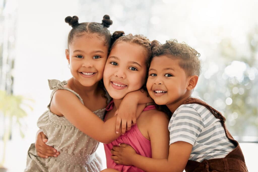 Three siblings smiling together after seeing a Las Vegas dentist.